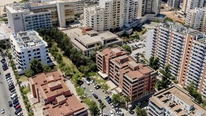 Vue aérienne d’une ville côtière avec de hauts immeubles, une plage et un parking.