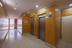 A hallway with wooden paneling, two elevators, and a tiled floor. - Apartment 'Paraíso Da Rocha' with Mountain View, Wi-Fi and Air Conditioning (Portimão)