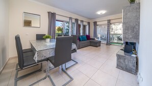 Un espace de vie moderne comprenant une table à manger, des chaises, un canapé et un meuble de rangement intégré pour les appareils multimédias.