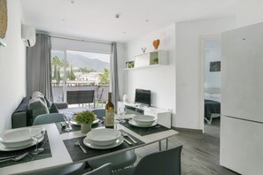 A modern kitchen with a dining area, a TV, and a balcony with a view of the city. - Torremolinos. Comfortable Apartment. Pool (Torremolinos)