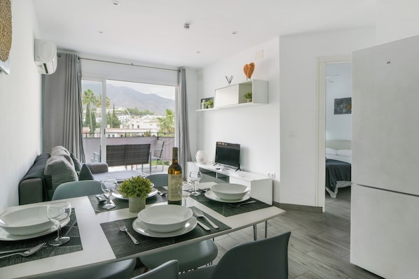 Une cuisine moderne avec un coin repas, un téléviseur et un balcon offrant une vue sur la ville.