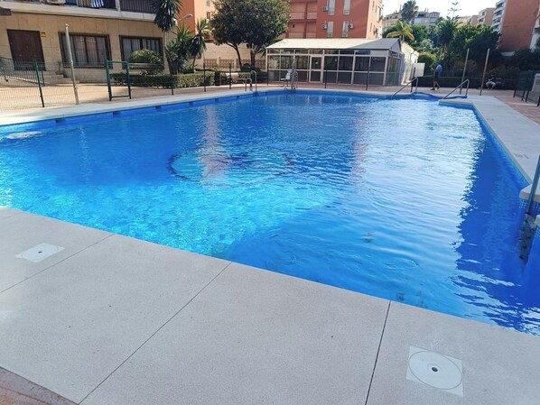 A rectangular swimming pool with clear blue water, surrounded by a tiled deck.