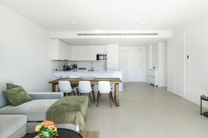Un espace de vie moderne comprenant un coin repas, une kitchenette et un canapé agrémenté d’un objet décoratif.