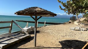 A beach with a wooden structure, a sandy area, and a view of the sea. - Spacious studio on the seafront, newly renovated (Le Gosier)