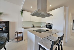 A modern kitchen with a central island, a built-in oven, and a microwave.