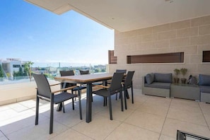 A modern outdoor dining area with a table and chairs, a sofa, and a view of the city. - Luxury living with sea views. Walk to the beach (La Cala de Mijas)