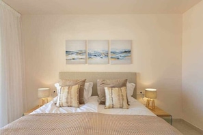A hotel room with a bed, two bedside lamps, and three wall-mounted paintings. - Luxury living with sea views. Walk to the beach (La Cala de Mijas)