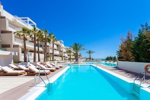 A swimming pool with lounge chairs and palm trees, surrounded by a building with balconies. - Walk to Beach! Premium apartment pool & gym (La Cala de Mijas)