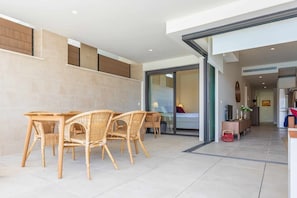 A modern interior with a dining area featuring wicker furniture, a kitchen with a refrigerator, and a glass door leading to a living space. - Walk to Beach! Premium apartment pool & gym (La Cala de Mijas)