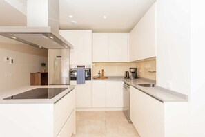 A modern kitchen with white cabinetry, a built-in oven, and a stainless steel range hood. - Walk to Beach! Premium apartment pool & gym (La Cala de Mijas)