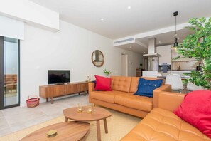 A modern living room with a leather sofa, a television, and a dining area with a table and chairs. - Walk to Beach! Premium apartment pool & gym (La Cala de Mijas)