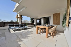An outdoor patio with a dining table and chairs, a covered seating area, and a view of the city skyline. - Modern 3 bedroom apartment, very close to beach (La Cala de Mijas)