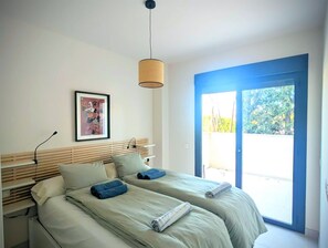 A bedroom with two beds, a ceiling light, a framed picture, and a view through a door. - Modern 3 bedroom apartment, very close to beach (La Cala de Mijas)