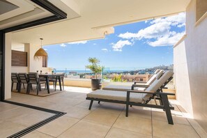 Ein Balkon mit Essbereich, Liegestühlen und Meerblick.