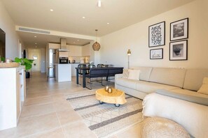 Ein modernes Wohnzimmer mit einer Couch, einem Couchtisch und einem Essbereich mit Stühlen.