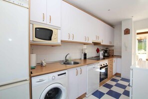 A compact kitchen with white cabinets, a microwave, a dishwasher, and a washing machine.