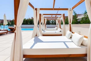A sunlit outdoor lounge area with a pool, wooden pergola, and white cushioned seating. - Seaviews & pool close to beach (La Cala de Mijas)