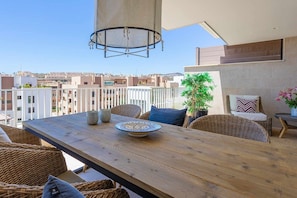A balcony with a wooden table, wicker furniture, a potted plant, and a view of the cityscape. - Seaviews & pool close to beach (La Cala de Mijas)