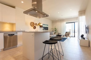 A modern kitchen with a built-in dishwasher, a central island with stools, and a dining area with a sofa and coffee table. - Seaviews & pool close to beach (La Cala de Mijas)