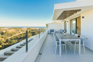 A modern outdoor balcony with a dining table and chairs, overlooking a coastal landscape. - Premium penthouse with sea views (La Cala de Mijas)