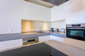 A modern kitchen with built-in appliances, a stainless steel sink, and a dishwasher.
