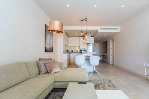 A modern living room with a sectional sofa, a coffee table, and a dining area with chairs.