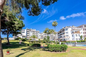 A residential building with multiple balconies, a swimming pool, and a well-maintained garden with a gazebo.