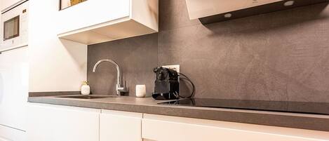 Een moderne keuken met witte kasten, een roestvrijstalen spoelbak en een koffieapparaat.