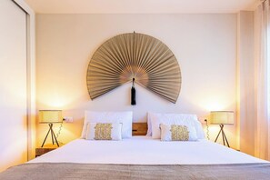 A hotel room with a large bed, two bedside lamps, and a wall-mounted fan. - Premium apartment close to beach with 2 pools (Calahonda)