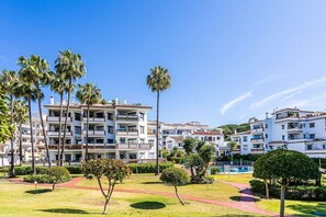 A multi-story hotel with balconies, a swimming pool, and a well-maintained garden with palm trees. - Premium apartment close to beach with 2 pools (Calahonda)
