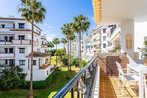 A balcony with a view of a residential area, including palm trees and a tiled patio. - Premium apartment close to beach with 2 pools (Calahonda)