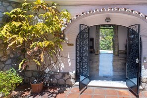 A stone building entrance with a potted plant and a metal gate. - Luxury villa with private tennis & heated pool (Mijas)