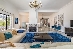 A spacious living room with a fireplace, a blue carpet, and modern furniture. - Luxury villa with private tennis & heated pool (Mijas)