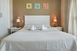 Une chambre d’hôtel avec un grand lit, deux tables de chevet et des lampes fixées au mur.