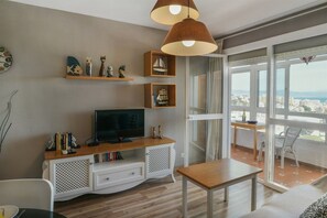 Una sala moderna con televisor, estanterías de madera y un balcón con vistas.