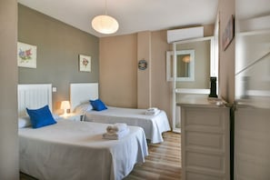 Una habitación de hotel con dos camas, un escritorio pequeño, un espejo y una puerta.