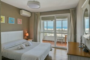 Une chambre d’hôtel équipée d’un lit, d’une table de chevet, d’une lampe, d’une fenêtre donnant sur la ville et d’un appareil de climatisation.
