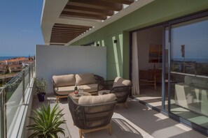 Ein Balkon mit einer Sofagarnitur, einem Esstisch und Blumentöpfen.