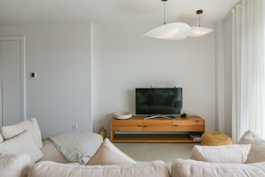 A modern living room with a sofa, a wooden TV stand, and pendant lighting.