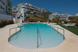 Ein Schwimmbecken mit klarem, blauem Wasser, umgeben von einer gepflasterten Terrasse und Metallgeländern.