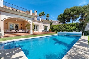 Ein Pool mit einer Terrassenanlage, Liegestühlen und einer überdachten Sitzgelegenheit.