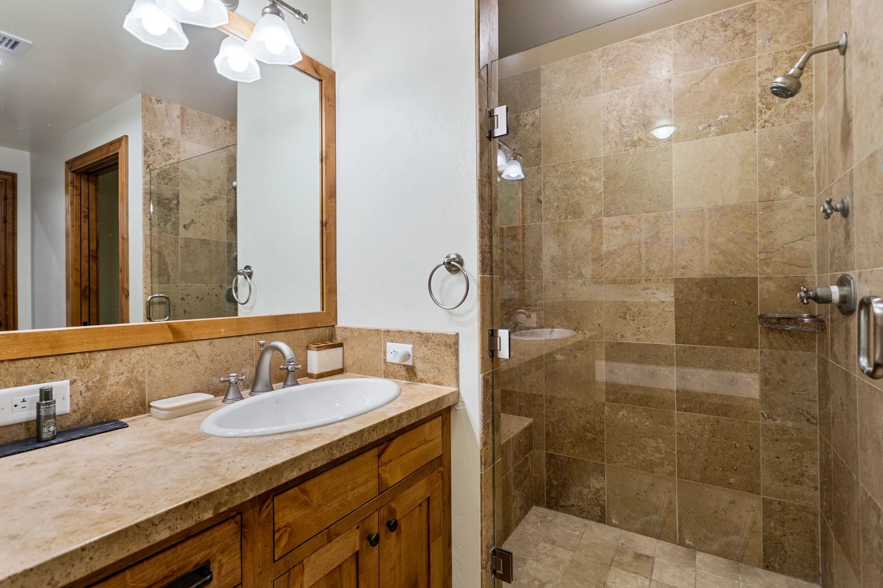 Un baño con lavamanos, espejo y ducha.