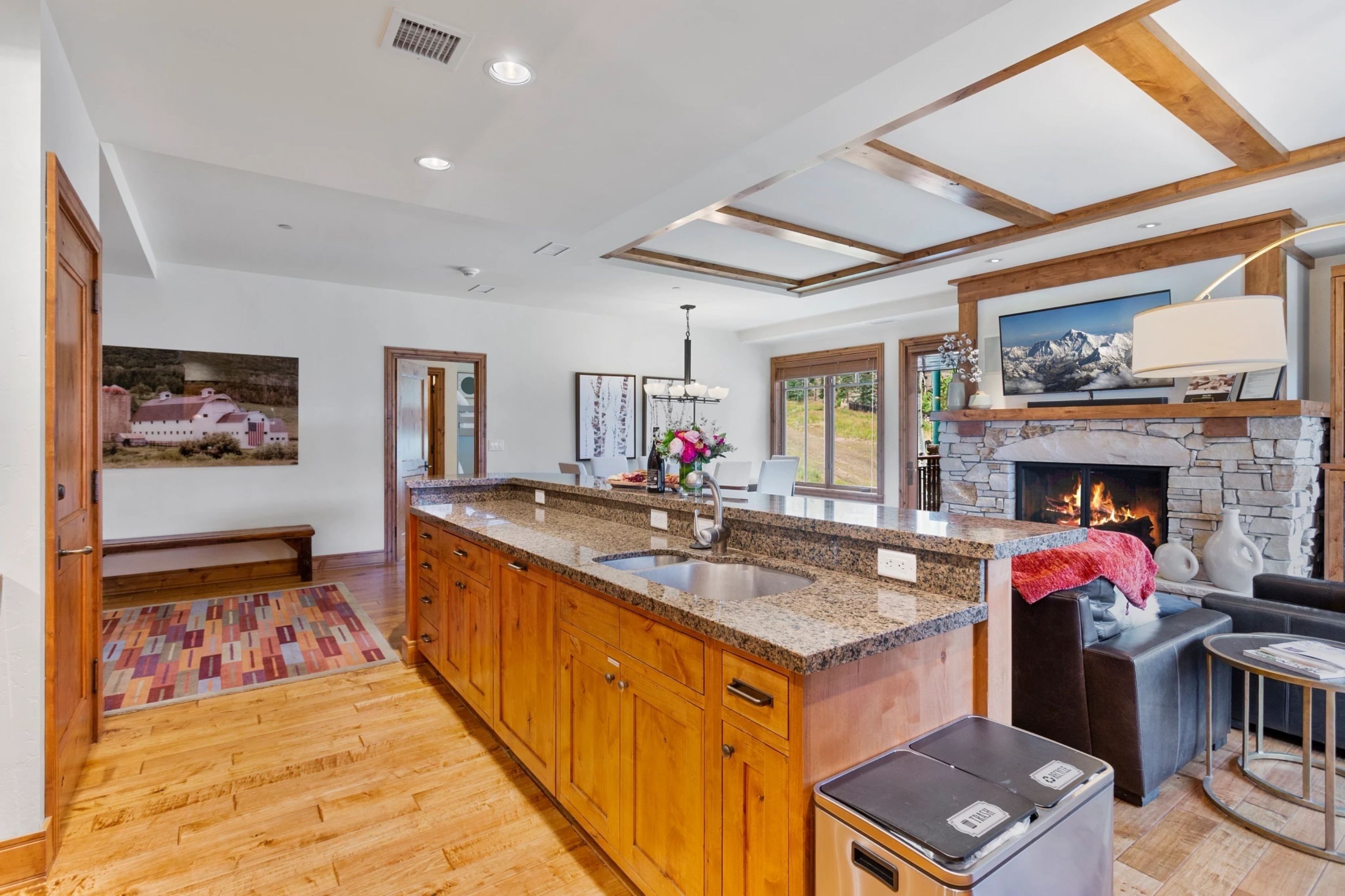 A spacious kitchen with wooden cabinets, granite countertops, and a stone fireplace.
