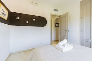 A bedroom with a bed, a dark accent wall, and a hallway leading to a door. - Beautiful views from 2 terraces with pool &parking (Mijas Golf)