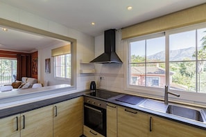 A modern kitchen with a large window, a stove, and a sink.