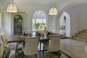 A dining area with a wooden table and upholstered chairs, an arched doorway, and a staircase leading to an upper level. - Villa, heated pool, golf, games, BBQ! (Mijas Golf)