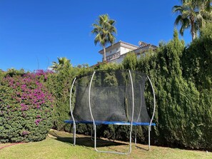 A trampoline in a garden with a house in the background. - Villa, heated pool, golf, games, BBQ! (Mijas Golf)