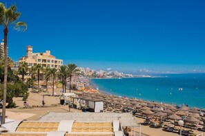 A beach with umbrellas, a building, and a clear blue sky. - Seaview apartment with terrace. Walk to beach (Benalmadena)