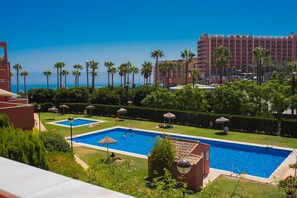 Een hotel met een zwembad, palmbomen en uitzicht op de oceaan.