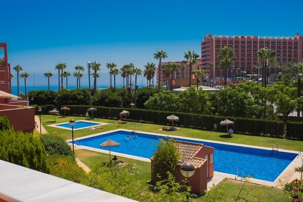 Un hotel con zona de piscina, palmeras y vistas al océano.